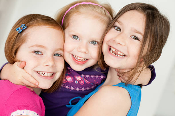 クローズアップの 3 つの幸せの姉妹ぴったり - embracing smiling gap children only ストックフォトと画像