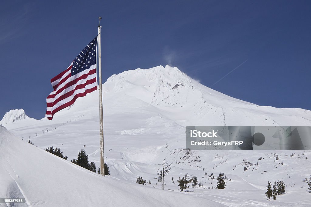 Mount Hood Peak with Flag Blue Sky at Timberline Oregon Summit of Mt Hood ( South Side ) located in Northwest Oregon. Taken on a sunny Spring like day. This photo is located near Timberline Lodge, a National Historic Landmark and has the top of a ski lift visible. Flag Stock Photo