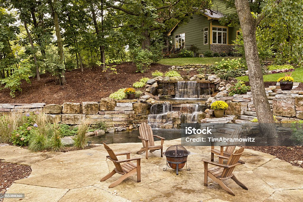 Perfect Backyard Landscaping Beautiful landscaping with waterfall, koi pond, and stone patio with wooded surroundings. Landscaped Stock Photo