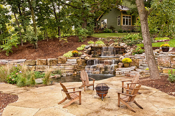 Perfect Backyard Landscaping Beautiful landscaping with waterfall, koi pond, and stone patio with wooded surroundings. pond stock pictures, royalty-free photos & images