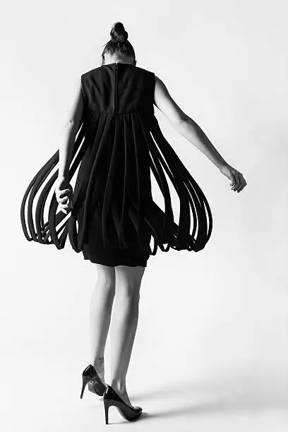 A model in an avant garde dress twirls on a white background.