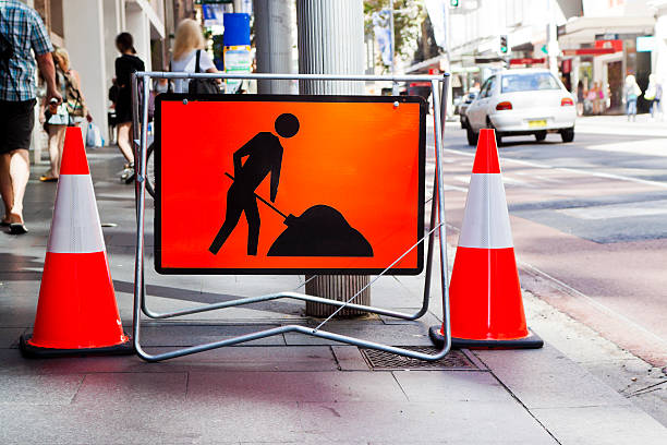 Roadwork red sign and two red cones on street, full frame horizontal composition