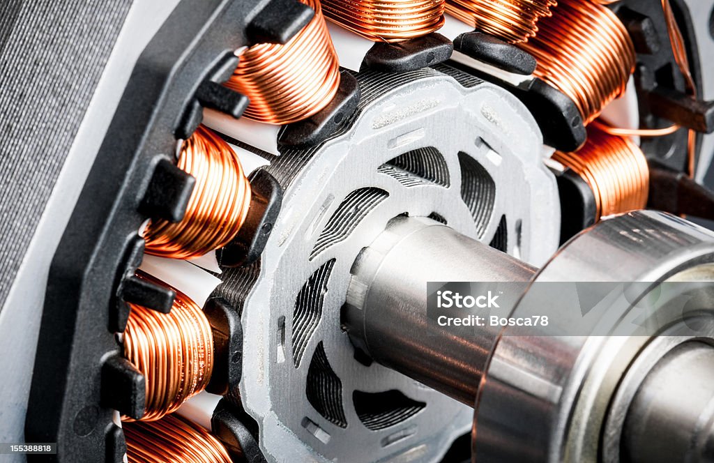 Permanent magnet motor disassembled close-up Detail of copper winding, stack and shaft of a  electric permeant magnet motor for home appliances. Selective focus and white background. Electric Motor Stock Photo