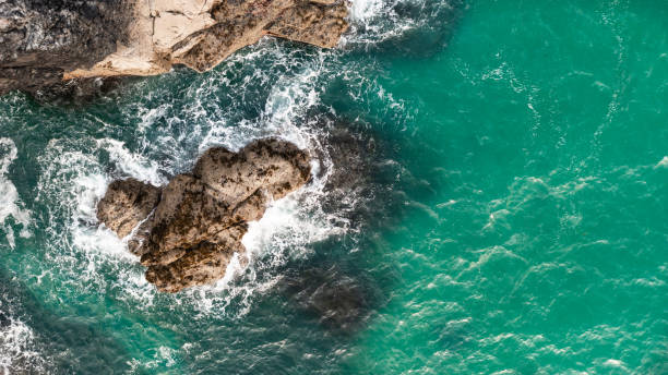 istock Aerial view directly above waves crashing onto rocky cliffs in Cornwall 1553888268