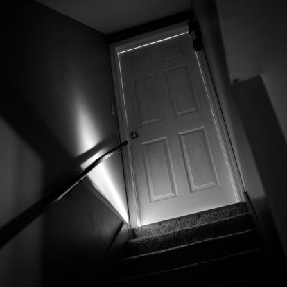 Shot of a basement door in the dark with bright sunlight bursting through the bottom. Medium format film (Kodak T-MAX 400) with some 400 ISO film grain visible.