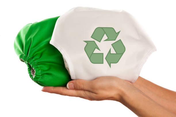 Female hands holding two cloth diapers one with recycling symbol stock photo