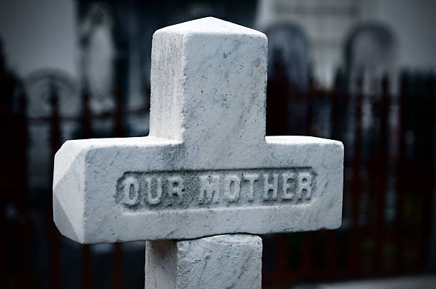 Our Mother - engravement on tombstone The words "Our Mother" engraved on a tombstone on a cemetery at night. Selective focus on the centre. engravement stock pictures, royalty-free photos & images