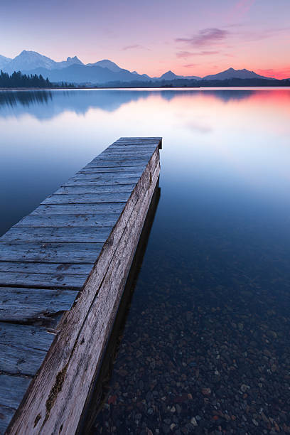 istock tranquil sunset at lake bannwaldsee with jetty, bavaria - germany 155388944