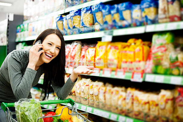 istock Attractive woman laughing on phone while grocery shopping 155388970