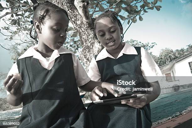Schoolgirls In Uniform On Digital Tablet Outdoors Stock Photo - Download Image Now - African Ethnicity, Bahamas, Child