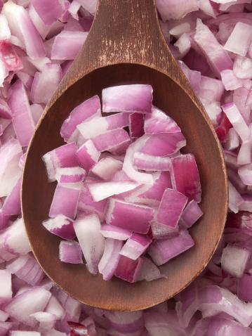 Top view of wooden spoon full of diced red onions