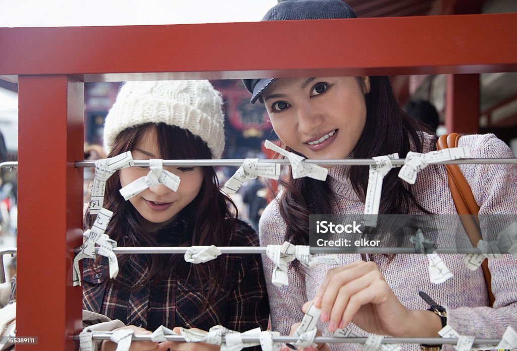 Два молодых женщин японской завязывать omikuji (Записка с предсказанием). - Стоковые фото Азиатская культура роялти-фри