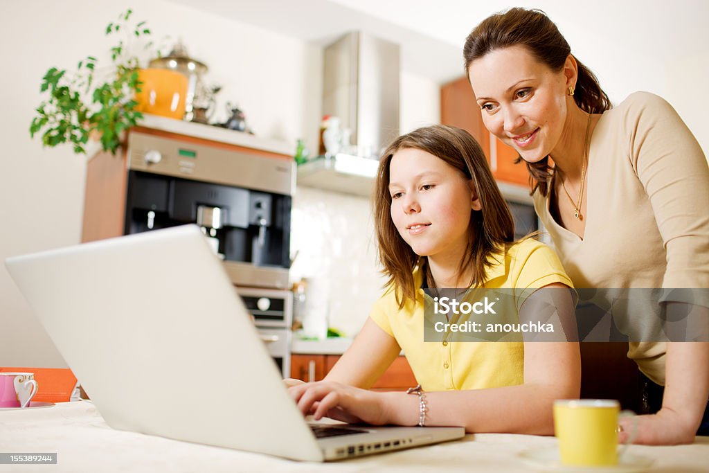 Felice madre con figlia utilizzando il computer portatile a casa - Foto stock royalty-free di Adolescente