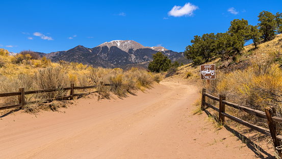 A bright sunny Spring day at the entrance of a treacherous sandy desert road, with Mt. Herald towering in background. Great Sand Dunes National Park, Colorado, USA.