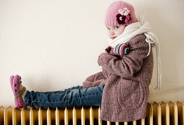 Little girl sitting on radiator stock photo