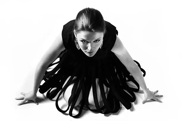 A model crouches and looks at the camera in a vintage avant-garde dress.