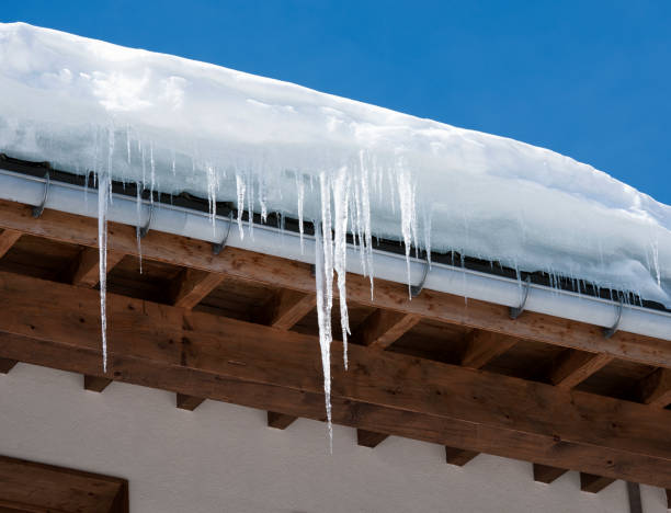 Icicles and Snow Overhanging a Roof Long icicles and snow overhaning the roof and gutter of a building. icicles melting stock pictures, royalty-free photos & images