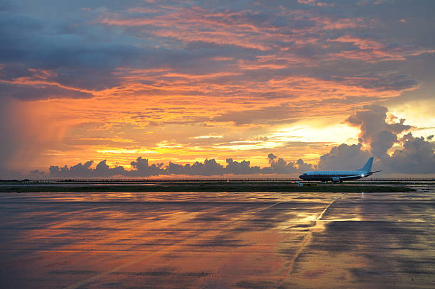 aeroplano gravare su tarrmac al tramonto - runway airport sky wet foto e immagini stock