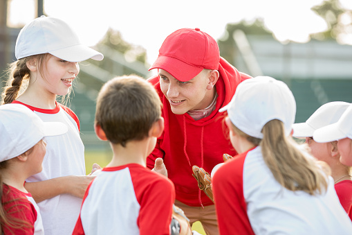 Coach talks with team of little league baseball players during game
