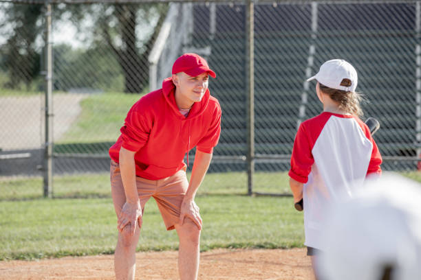 istock Coach gives instructions to little league baseball player before she bats 1553914820