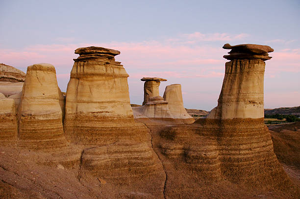 The hoodoos near Drumheller, Alberta, frame a pink sunset.