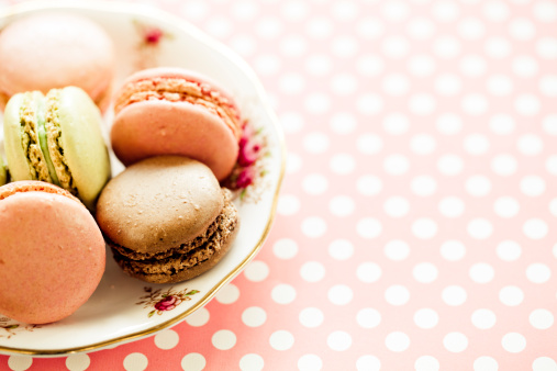 Variety of macaroons in a row on a fancy plate.