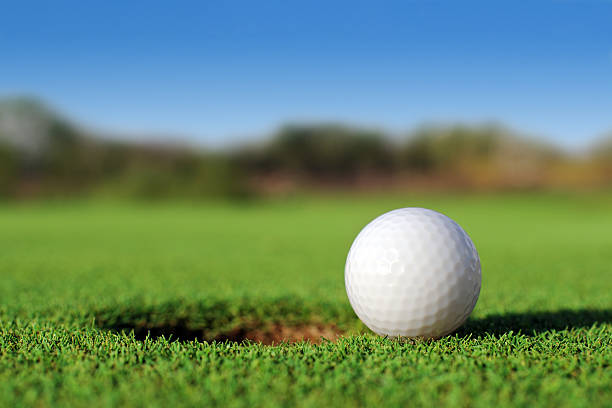 Ground level close up of golf ball close to hole Golf Ball Close To The Hole sports ball photos stock pictures, royalty-free photos & images
