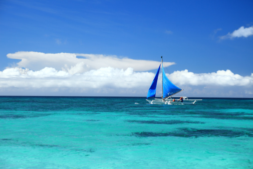 Outrigger sailboat sailing along the turquoise sea of ​​the island of Boracay, Philippines