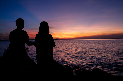 Silhouette lovers looking at the sea with the twilight of sunsets