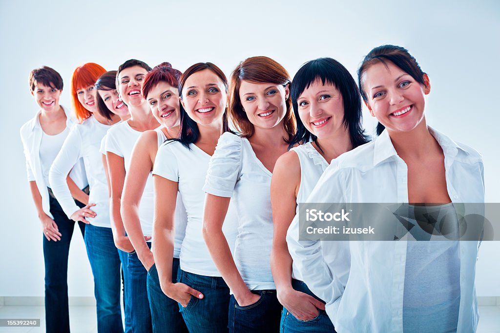 Women's team Group of women standing in the row, smiling at the camera against white background. Adult Stock Photo