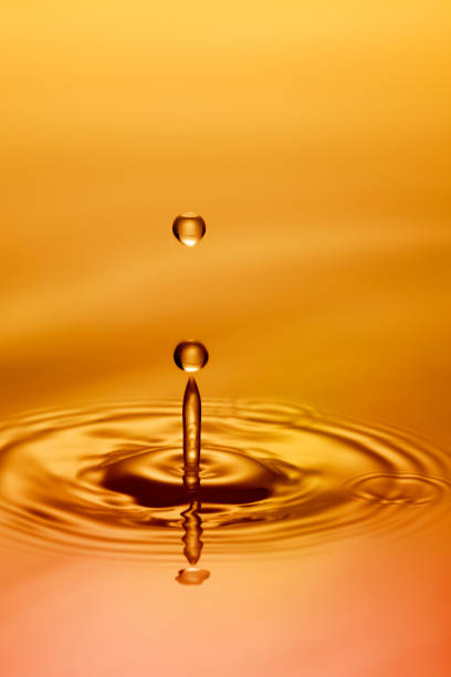 istock Single droplet rebounding off golden pool 155392241