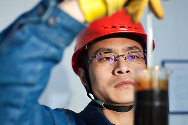 Engineer in red helmet with yellow gloves taking a sample