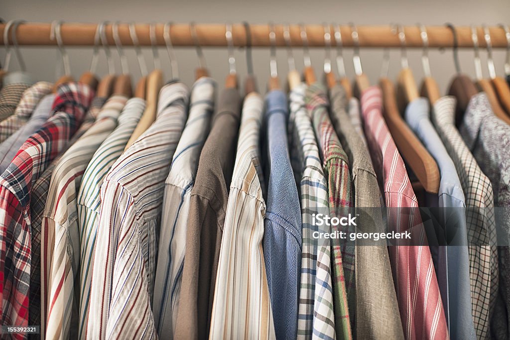 Shirts on Hangers A variety of shirts hanging on a wooden clothes rack. Clothing Stock Photo