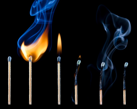 Close-up of matchstick igniting against black background.