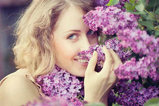 Beautiful woman smelling lilac flowers stock photo