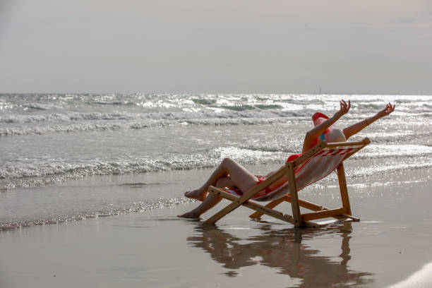 istock Selective focus on young Asian women wearing red bikinis and sleeping on a sunbed on a sand beach on a tropical island on a summer day holidays vacation with blue sea, beach, mountain, and sky backgrounds. 1553926459