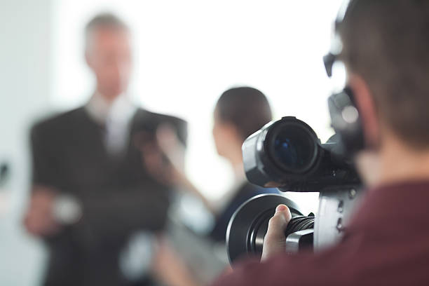 Interview. Video operator broadcasting an interview with people in background. spokesperson stock pictures, royalty-free photos & images