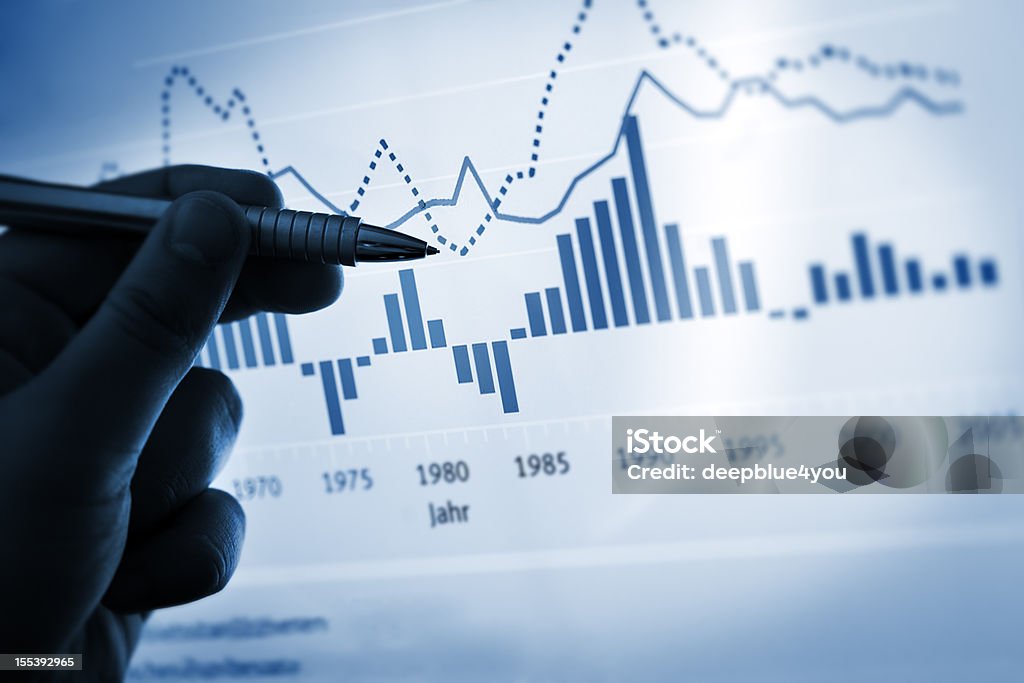 Hand pointing with pen on a computer chart / document chart Finance Stock Photo