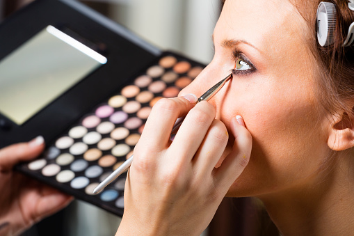 A pretty woman having makeup applied by a makeup artist.