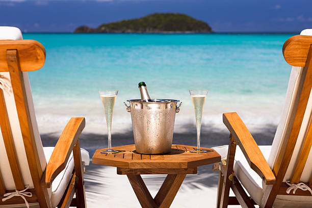 champagne and recliners on a tropical beach in the Caribbean bottle of champagne and two flutes on a luxury recliner set up at a tropical Caribbean beach honeymoon beach stock pictures, royalty-free photos & images