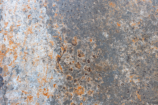Corrosion of an old metal sheet with traces of old paint and spots of rust showing through.