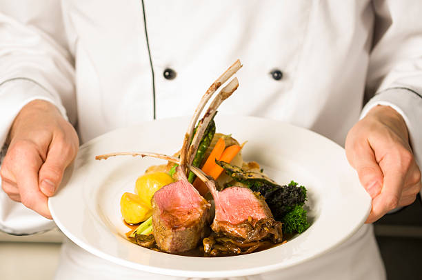 A freshly made rack of lamb being held by a chef  Chef holding a rack of lamb entree main course stock pictures, royalty-free photos & images