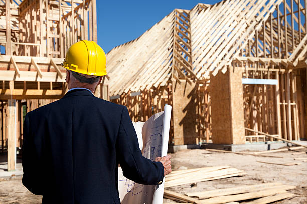 istock New home construction site with contractor in foreground. Framed buildings. 155394411