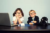 Young Business Children Sitting at Desk with Laptop