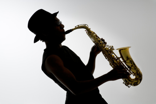 Young blond female playing a saxophone isolated on white background