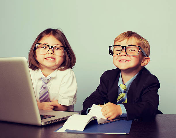 Business Children at Laptop in Office A young business duo are ready to take your business to the next tax bracket. cheesy grin stock pictures, royalty-free photos & images