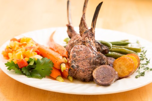 Sliced Rack of Lamb with Carrots and Green Beans on a white plate