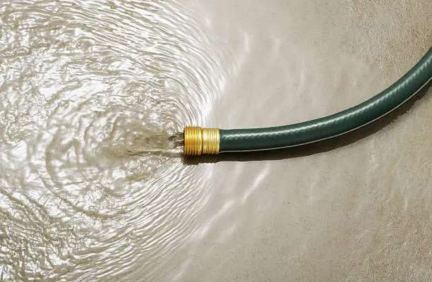 Gardening hose on concrete floor without water gun, wasting water concept.  More pictures...