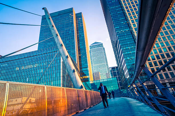 geschäftsmann zu fuß auf eine moderne brücke in canary wharf, london - city of london office building construction architecture stock-fotos und bilder