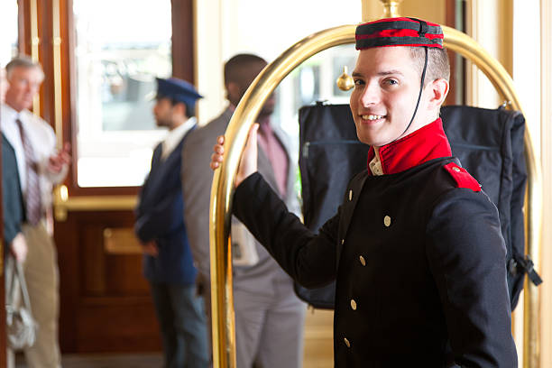 Bellhop holding luggage cart while waiting for hotel guests  bellhop photos stock pictures, royalty-free photos & images